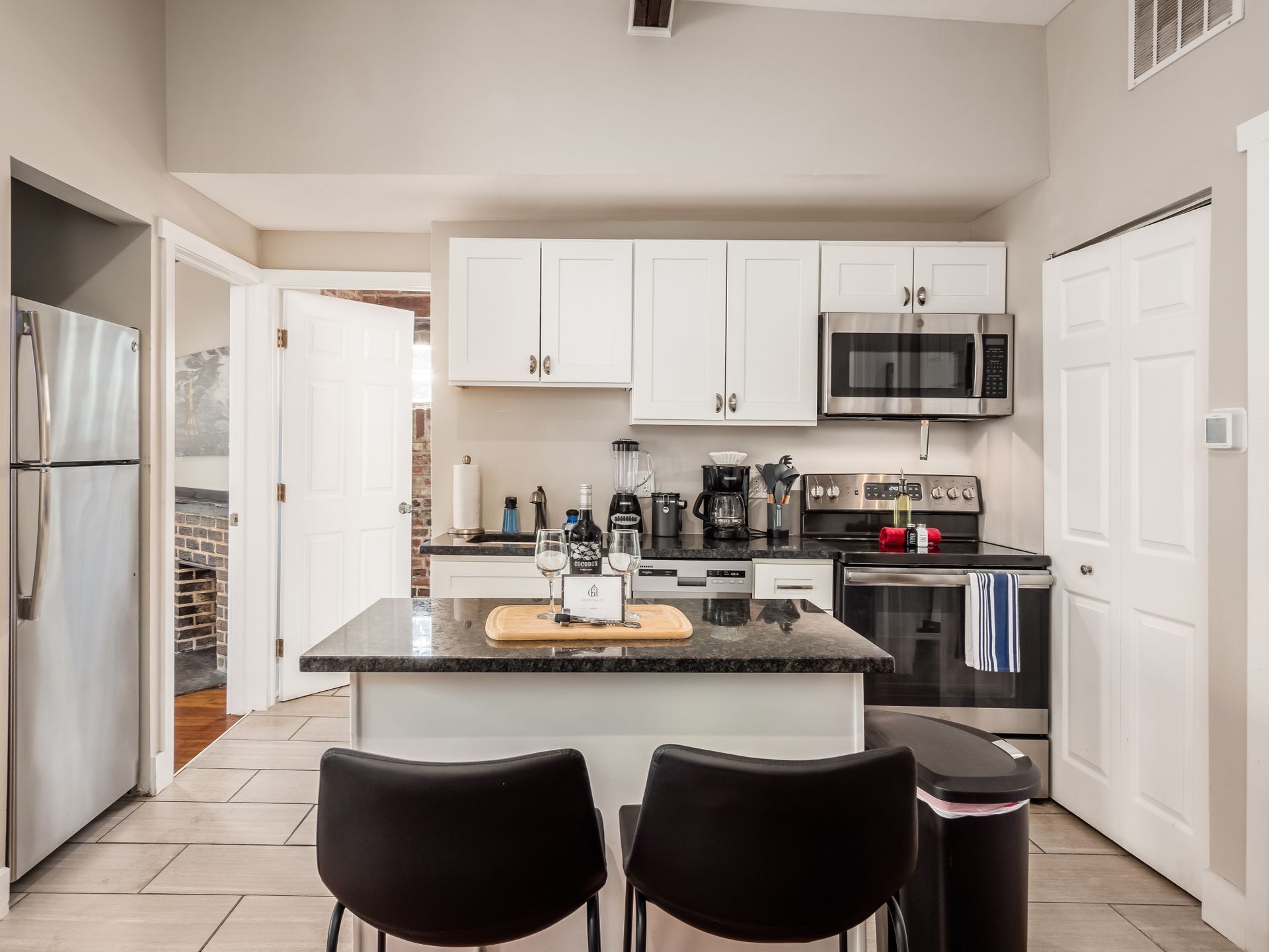 A modern kitchen with white cabinets, stainless steel appliances, and a central island with chairs.