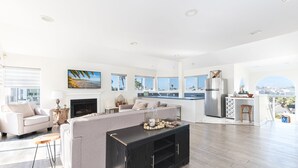 A spacious living area with a fireplace, a kitchen with a large island, and a view of the city.