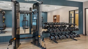A gym with weightlifting equipment, dumbbells, and exercise balls.