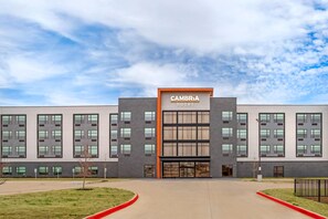 Un hotel moderno con una entrada destacada, ventanas amplias y un cielo despejado.