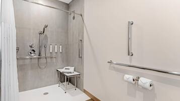 Un baño moderno con ducha, inodoro y barras de apoyo.