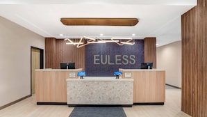 A reception desk with a 'FUELESS' sign, two computer stations, and a patterned wall.