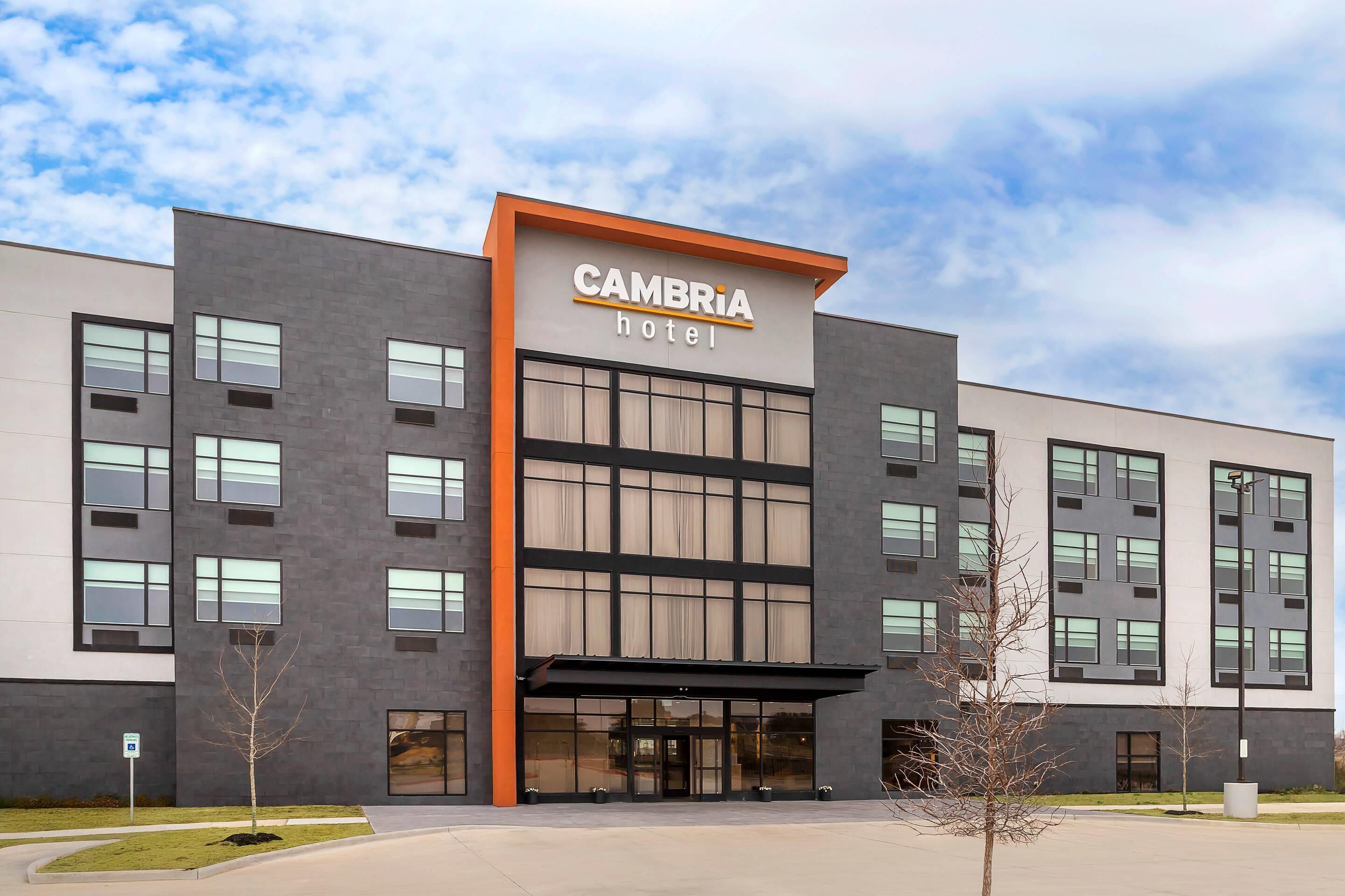 Een modern hotelgebouw met een opvallend bord waarop 'CAMBRIA hotel' staat.