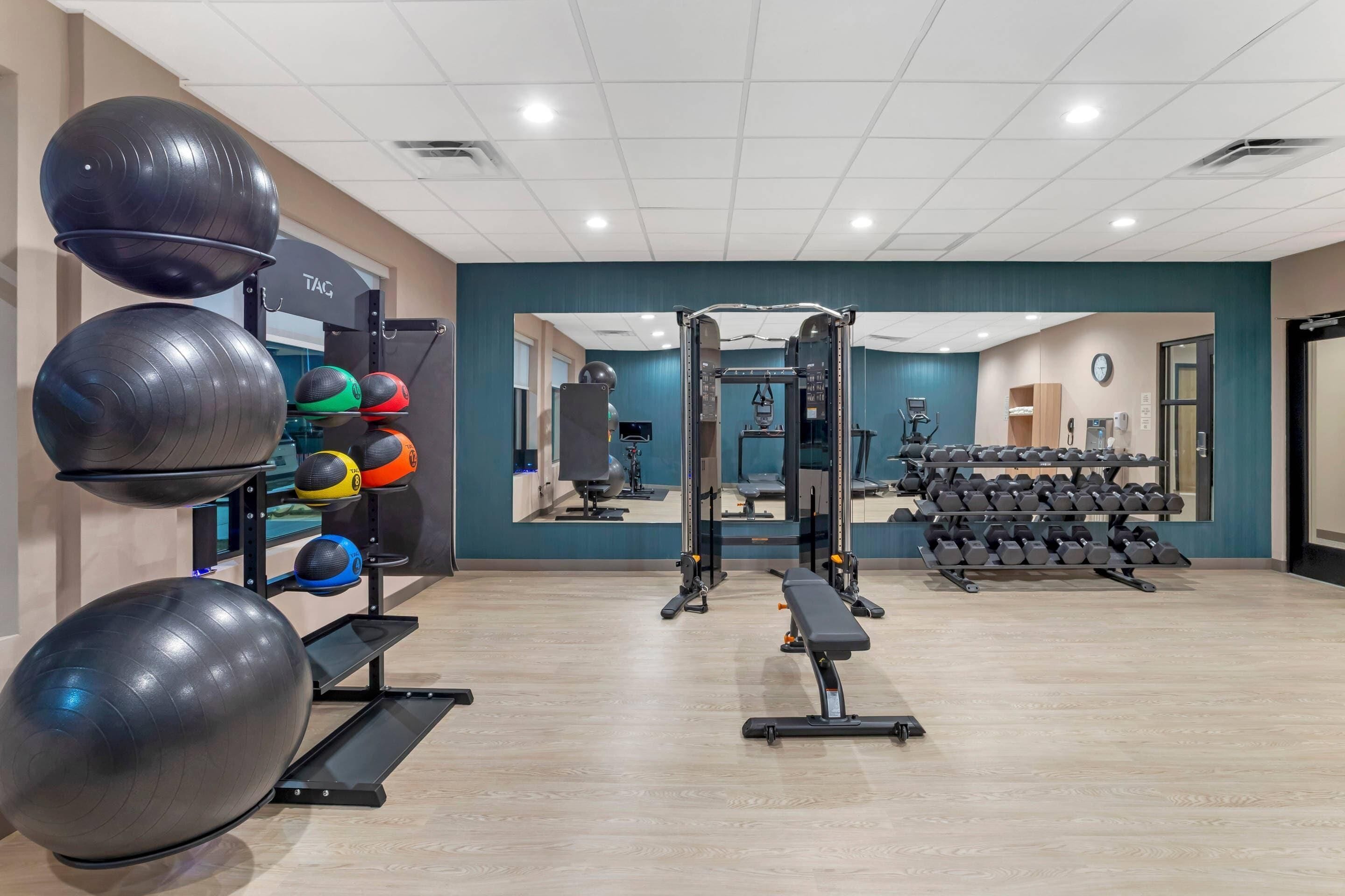 A gym with exercise equipment, a mirror, and a wall-mounted clock.