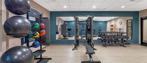 A gym with exercise equipment, a mirror, and a wall-mounted clock.