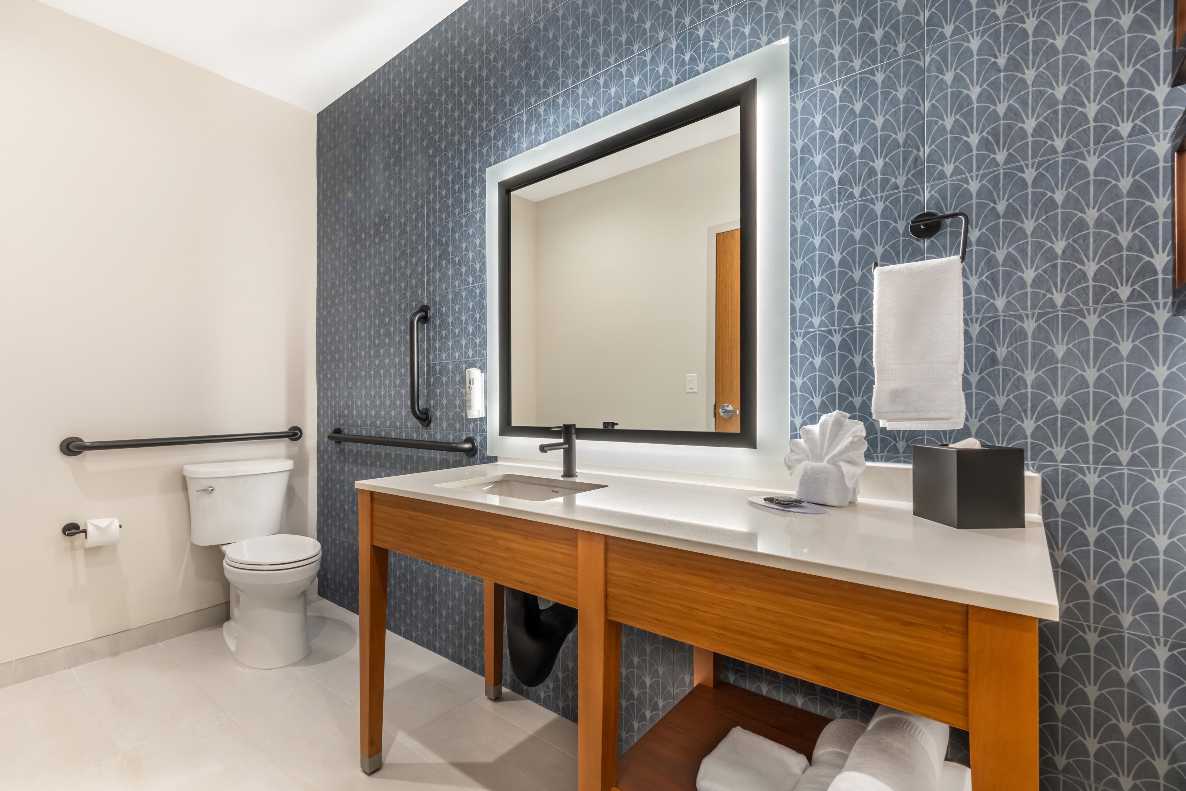 A modern bathroom with a white sink, mirror, and toilet.