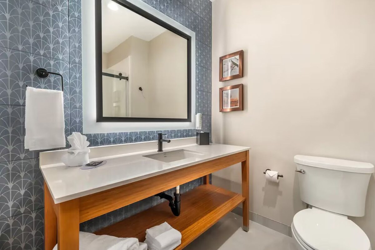 Une salle de bain avec un meuble-lavabo en bois, un grand miroir et des toilettes blanches.