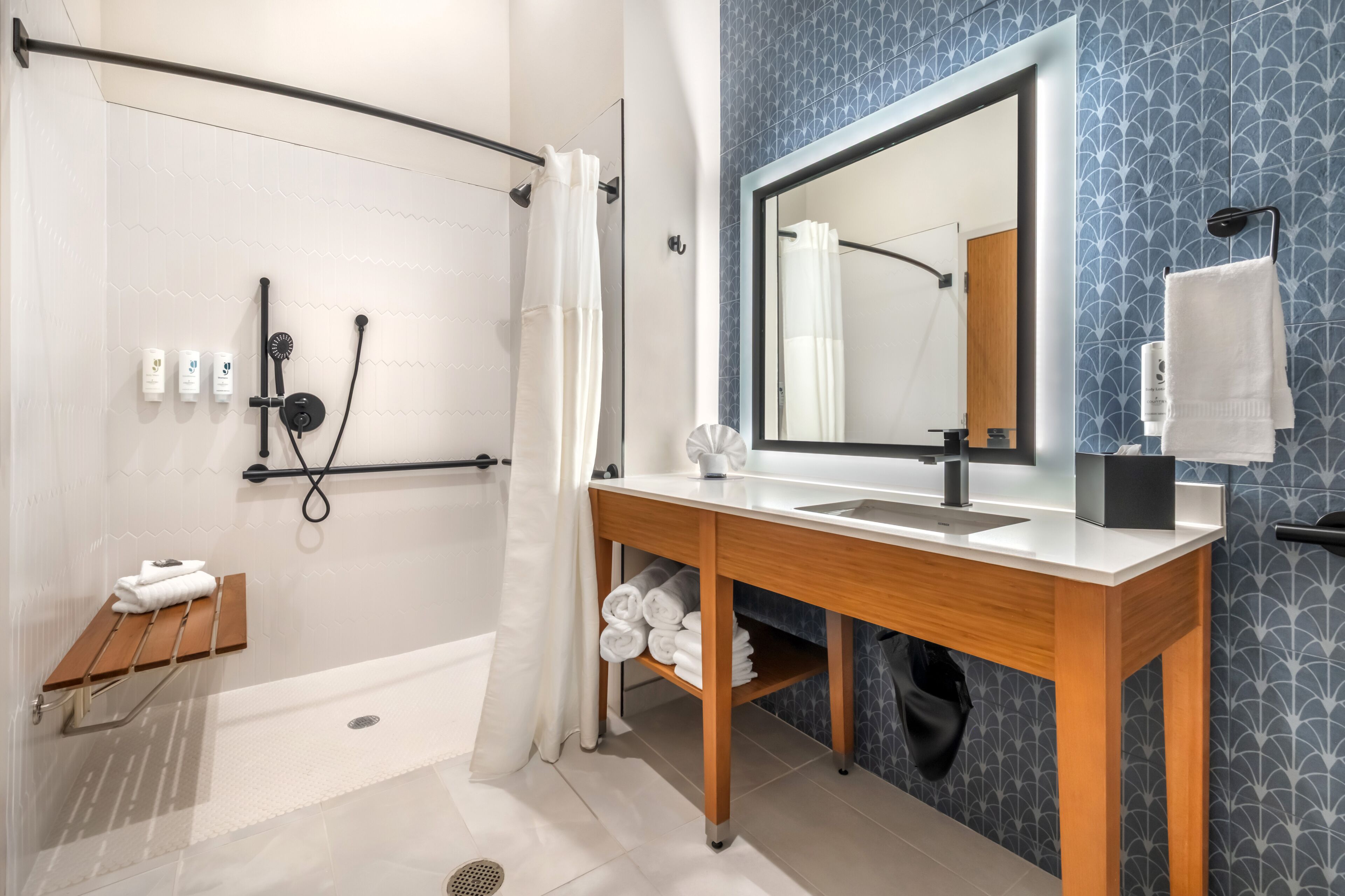 Een moderne badkamer met een douche, wastafel, spiegel en handdoekhouder.