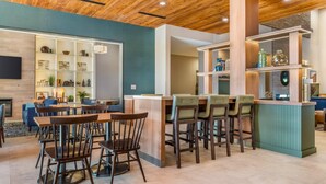 Un intérieur moderne avec un plafond en bois, un coin bar avec des tabourets et un espace salon avec des tables et des chaises.