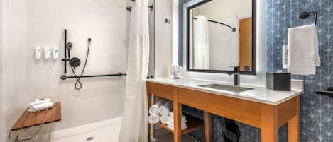 Un baño moderno con ducha, lavabo, espejo y toallero.
