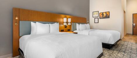 A hotel room with two beds, a wooden headboard, wall-mounted sconces, and a patterned carpet.