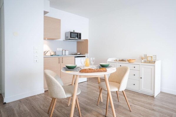 Una cucina moderna con tavolo, sedie e forno a microonde.