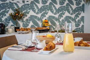 Colazione con un croissant, un bicchiere di succo d'arancia e una ciotola di frutta su un tavolo.