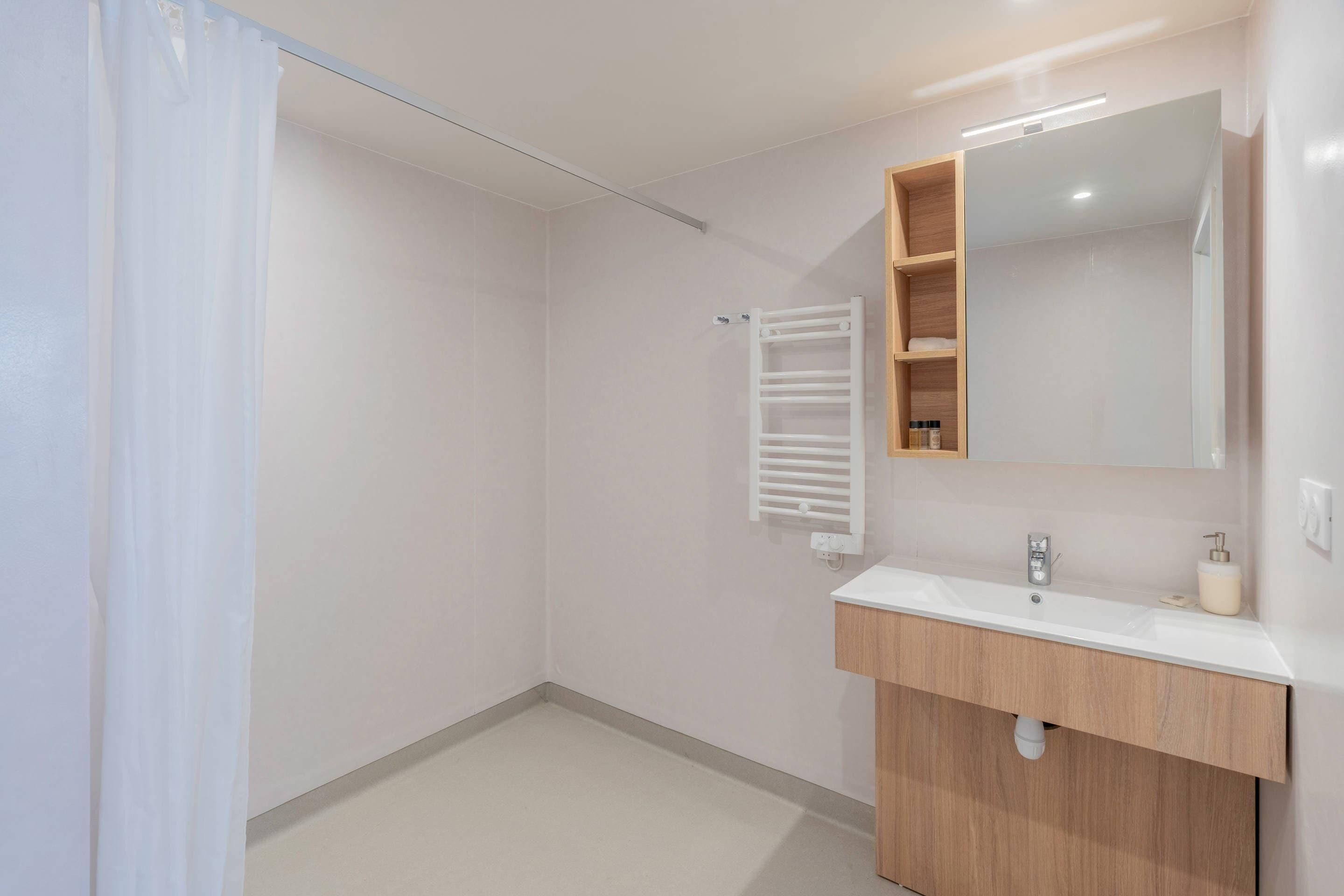 Un baño moderno con un lavamanos blanco, tocador de madera y un espejo.