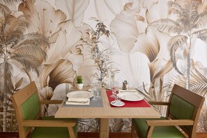 A dining table set with plates, glasses, and cutlery, surrounded by chairs with green cushions. - Quality Aparthotel Meaux (Meaux)