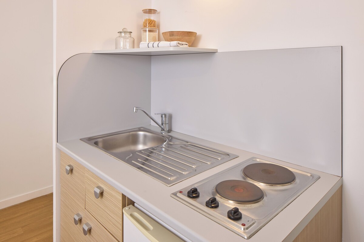 Une cuisine compacte équipée d’un évier, d’une cuisinière et de tiroirs de rangement.