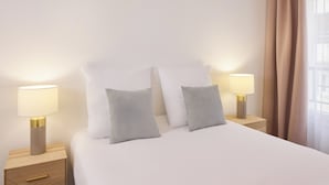 Ein ordentlich bezogenes Bett mit zwei Kissen, zwei Nachttischlampen und einem Nachttisch mit einer Schublade.