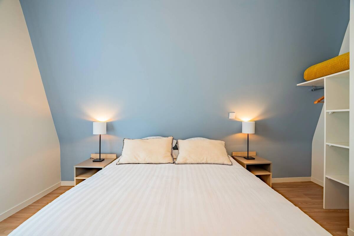Una camera da letto con un letto, due lampade da comodino, un comodino e una libreria a muro.