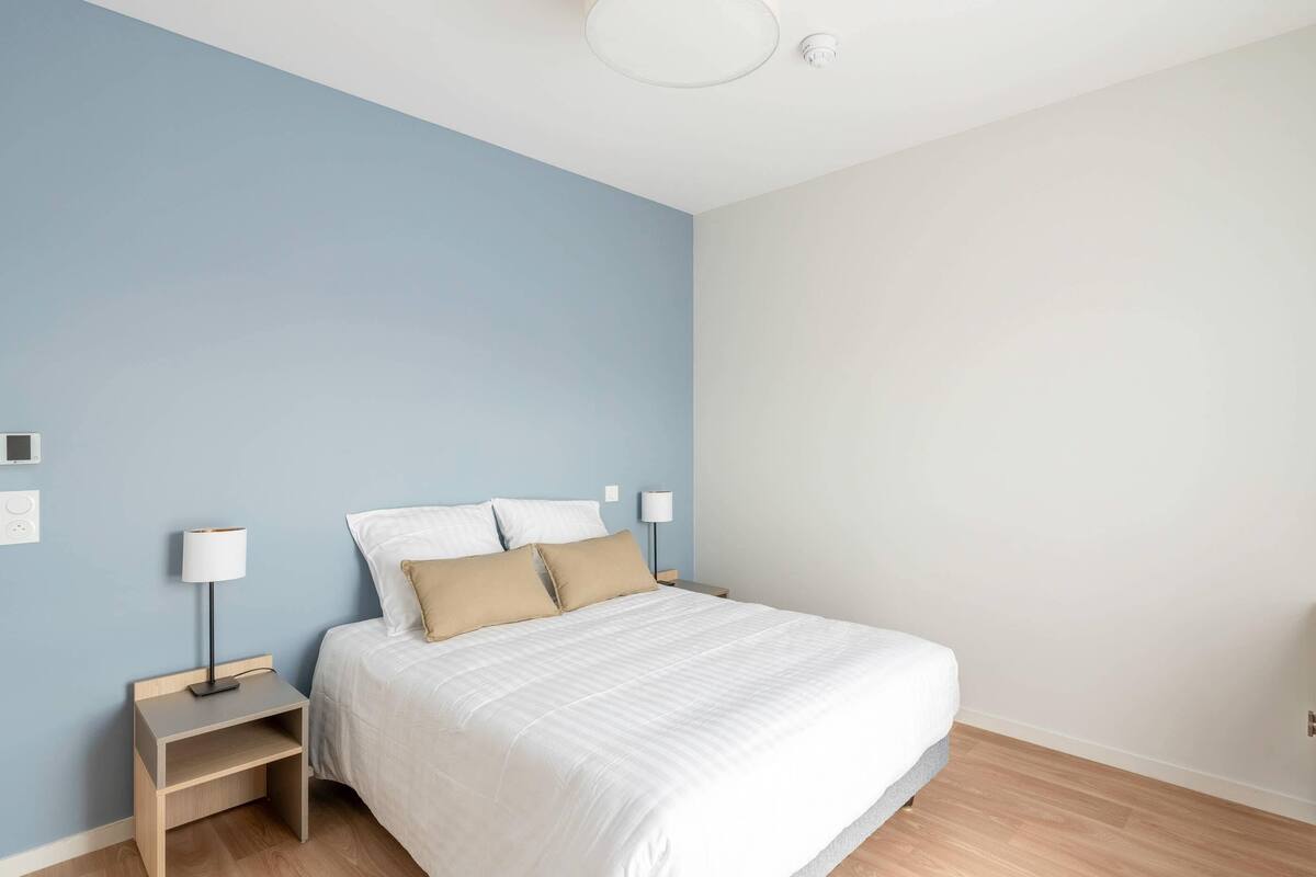 Camera da letto con un letto, comodini e una lampada a sospensione.