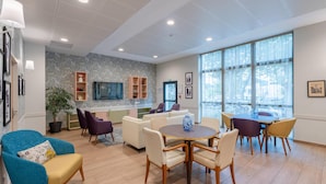 A modern hotel lobby with a seating area, a kitchen, and large windows. - Quality Aparthotel Périgueux (Perigueux)