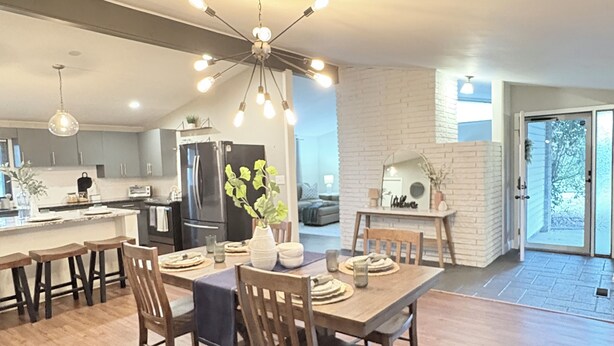 A spacious kitchen with a dining area, wooden flooring, and a modern chandelier. - Tulsa Expo Luxury Stay - 1 mi to Expo (Tulsa)