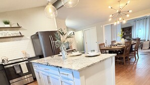 A modern kitchen with a central island, stainless steel appliances, and pendant lighting. - Tulsa Expo Luxury Stay - 1 mi to Expo (Tulsa)