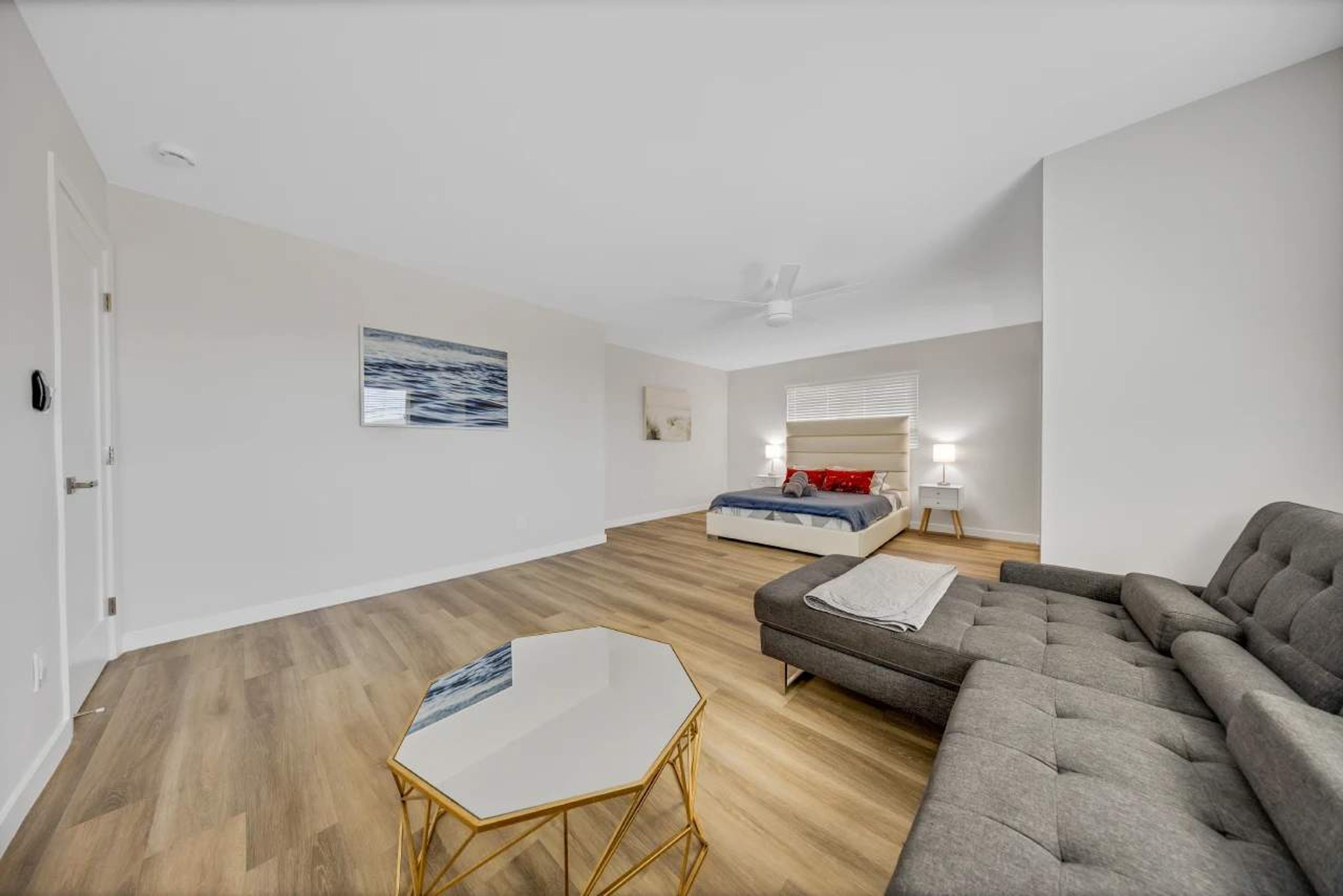 Una sala moderna con sofá, una mesita de centro y una cama con una mesita de noche.