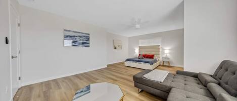 Una sala moderna con sofá, una mesita de centro y una cama con una mesita de noche.