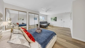 Ein modernes Schlafzimmer mit Bett, Nachttischen, einem Kleiderschrank, einer Couch und einem Deckenventilator.