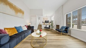 Ein modernes Wohnzimmer mit einem schwarzen Sofa, einem runden Goldtisch und einem blauen Sessel.