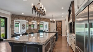 A spacious kitchen with a large island, stainless steel appliances, and a stone accent wall.