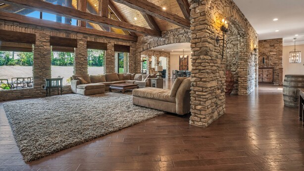 A spacious living room with a large sectional sofa, a stone accent wall, and wooden beams.