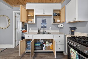 Une cuisine avec des placards ouverts, une cuisinière à gaz et un panneau fixé au mur.
