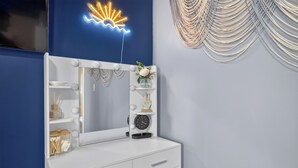 Een witte wastafel met spiegel, planken en een klok.