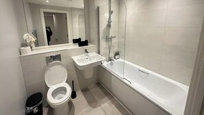 A modern bathroom with a toilet, sink, and bathtub.