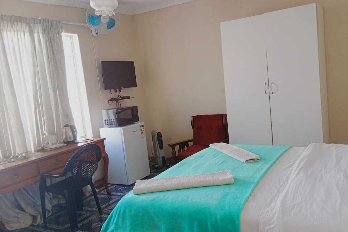 A hotel room with a bed, a desk, a TV, a microwave, and a wardrobe.