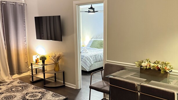 A modern hotel room with a dining area, a bed with a view, and a ceiling fan. - Quiet Corner ATL (Atlanta)