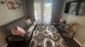 A modern living room with a sofa, a patterned rug, and a TV mounted on the wall. - Quiet Corner ATL (Atlanta)