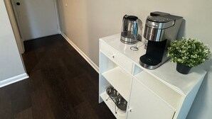 A hallway with a white cabinet, a coffee maker, a wine glass, and a small potted plant. - Quiet Corner ATL (Atlanta)