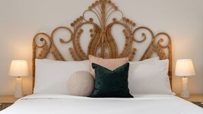 Ein Bett mit einem dekorativen Kopfteil, zwei Nachttischlampen und verschiedenen Kissen.