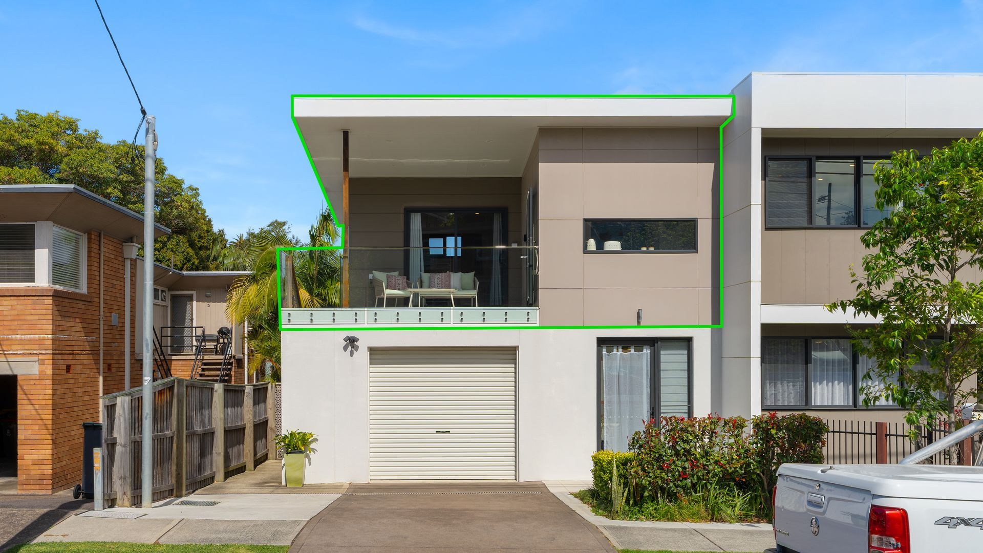 Een modern woonhuis met twee verdiepingen, een balkon, een garage en een oprit.