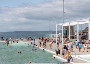 Ein überfüllter Schwimmteich mit Menschen, die das Wasser genießen und sich sonnen.