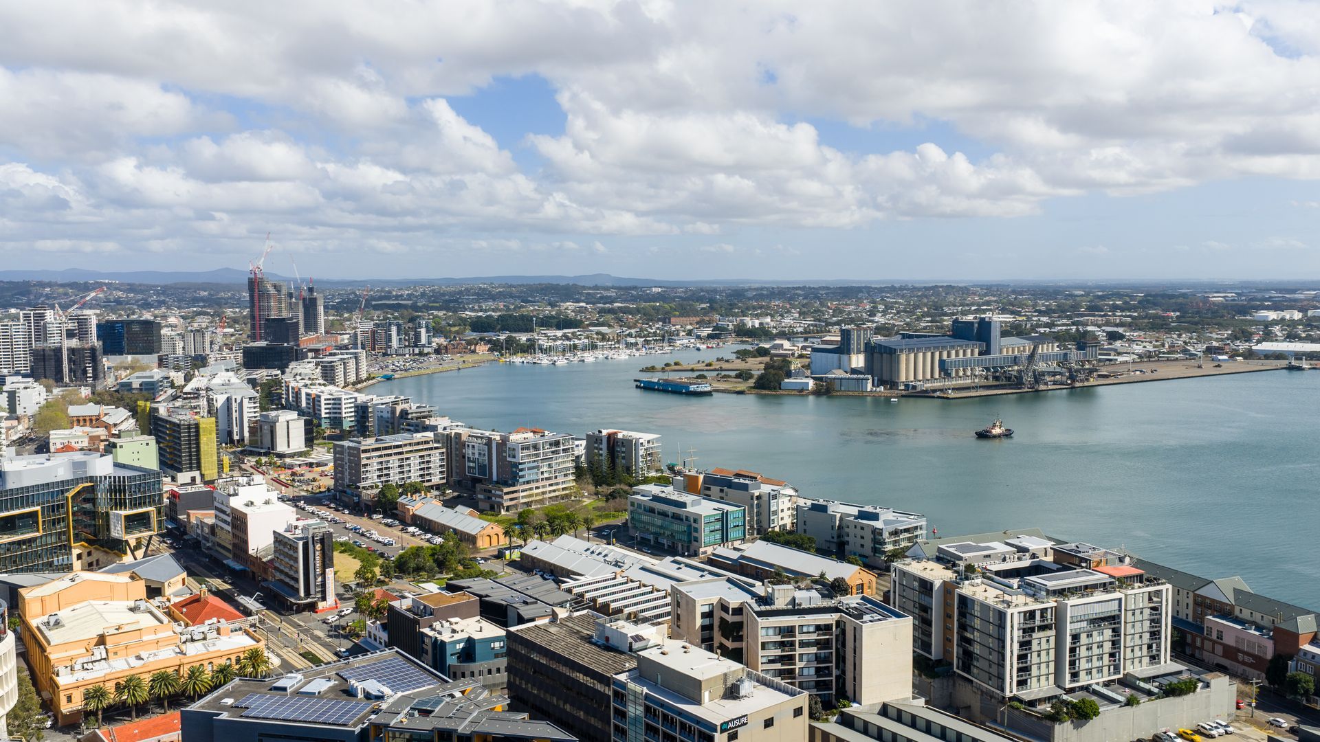 A cityscape with modern buildings, a river, and a distant view of mountains.