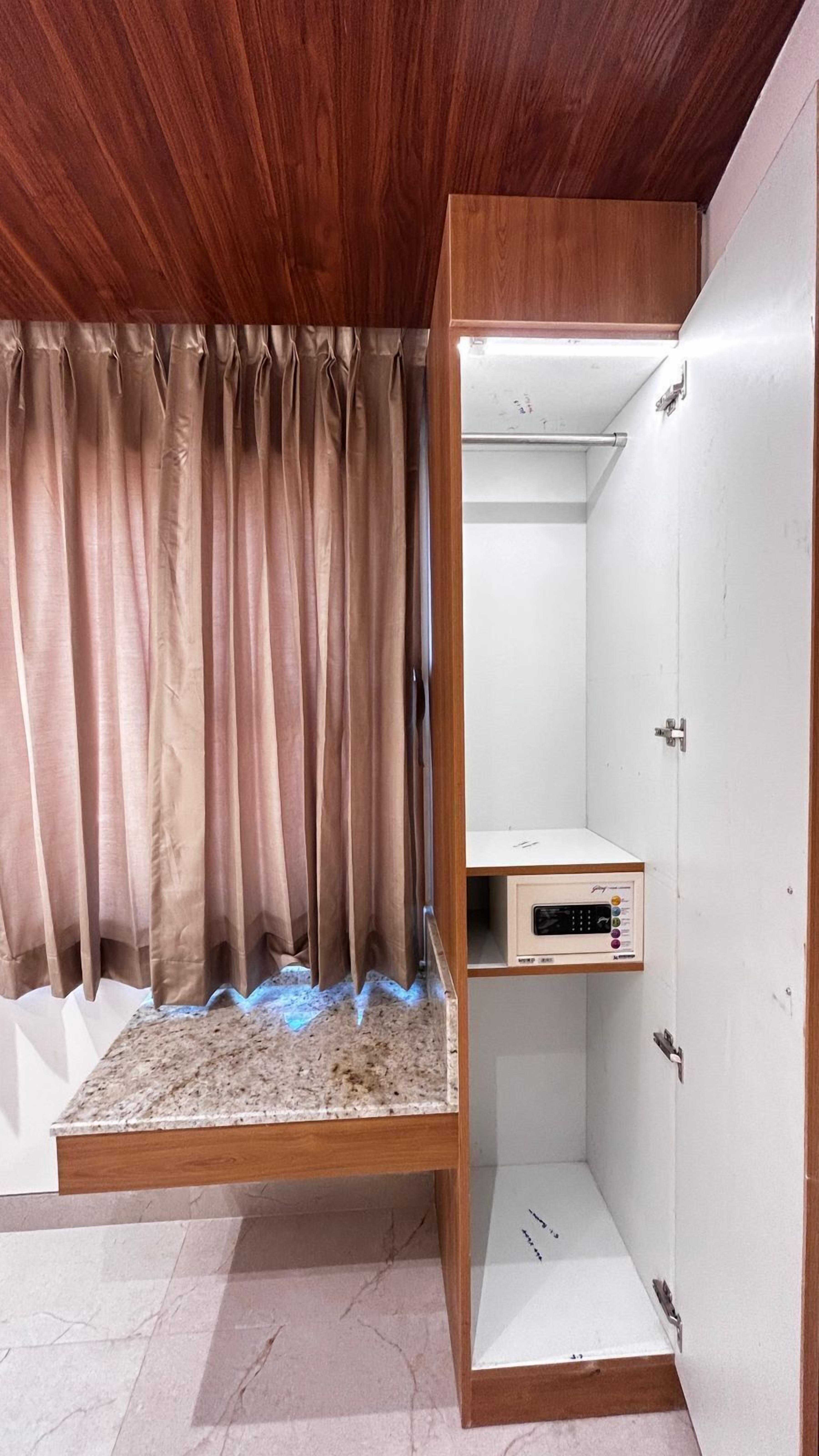 Une pièce avec un plafond en bois, un lit doté d’une tête de lit, une petite étagère et une porte blanche.
