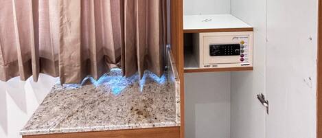 Una habitación con techo de madera, una cama con cabecera, un pequeño estante y una puerta blanca.