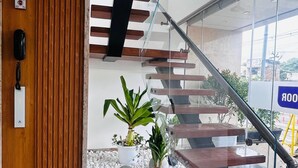 A modern staircase with glass railings and wooden steps, leading to an upper floor. - THE PARADISE PLATINUM (Kanchipuram)