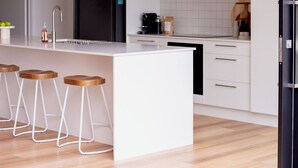 Eine moderne Küche mit einer zentralen Kochinsel, Barhocker und einem schwarzen Kühlschrank.