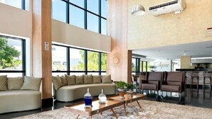 Uma sala de estar espaçosa com uma grande janela, um sofá, uma mesa de centro e uma área de refeições com cadeiras.
