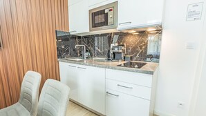 Una cucina compatta con forno a microonde, macchina del caffè e lavello.