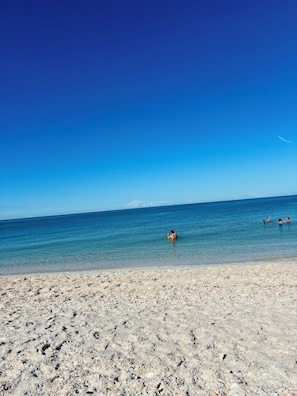 Una playa con agua azul cristalina y una orilla pedregosa.